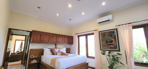 um homem deitado numa cama num quarto em Bali Emerald Apartments em Sanur