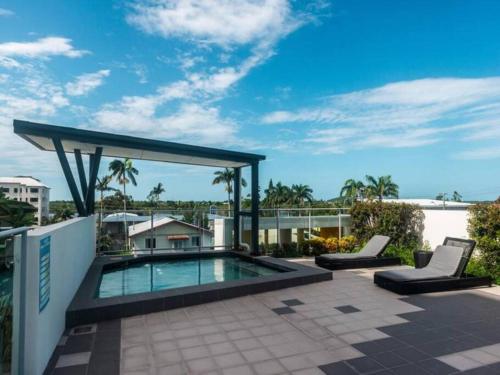 a patio with a swimming pool and two lounge chairs at Modern Riverside Suites in Mackay CBD with Pool and Parking in Mackay