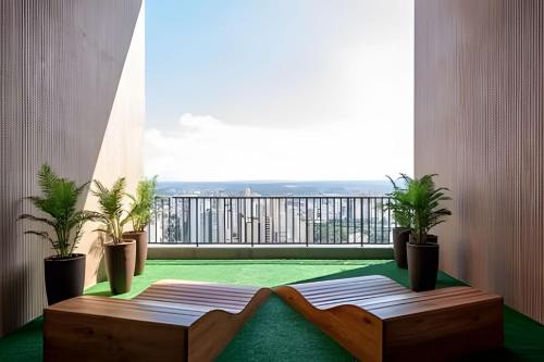 Elle comprend un balcon avec des plantes en pot et une grande fenêtre. dans l'établissement Flat Luxo 35º Andar • Vista Incrível da Cidade, à Goiânia