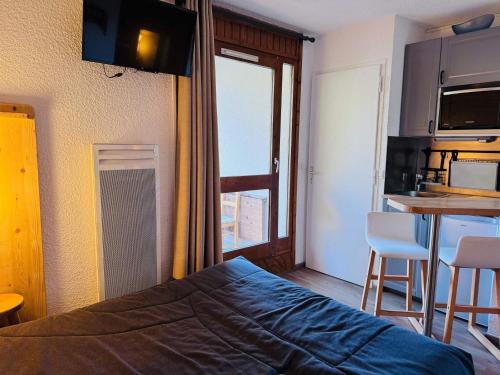 a bedroom with a bed and a kitchen with a table at Studette cosy pour 2 aux Deux Alpes avec balcon - FR-1-546-62 in Les Deux Alpes