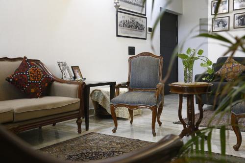 a living room with chairs and a couch and a table at Entire Vintage Apartment, Historic Heights Haven in Noida