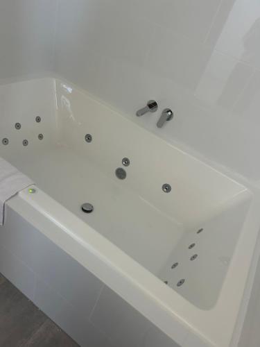 eine weiße Badewanne mit silbernen Armaturen in der Unterkunft Travellers Rest Motor Inn Swan Hill in Swan Hill