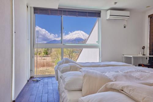 a room with four beds and a large window at The Deer Valley Yamanakako in Yamanakako