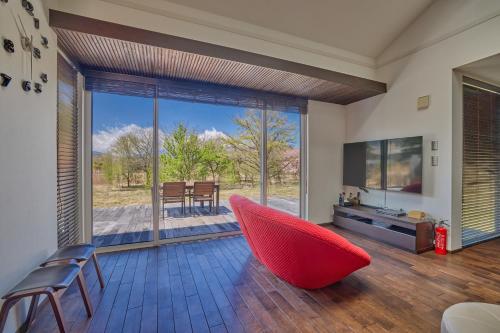 a living room with a red chair and a large window at The Deer Valley Yamanakako in Yamanakako