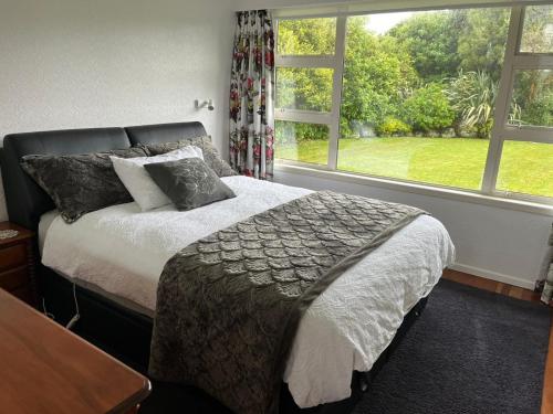 una camera da letto con un letto e una grande finestra di Mount Taranaki Basecamp 4BR Farmhouse & Games Room 