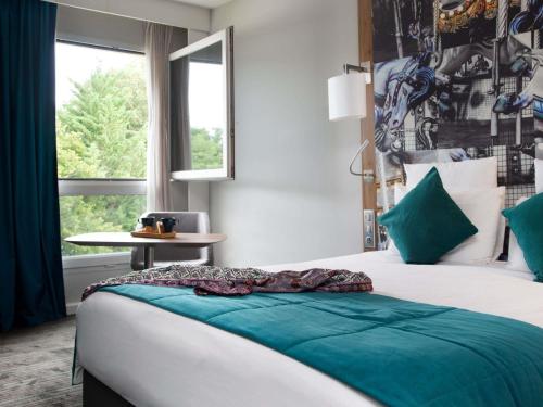 una camera da letto con un letto grande con cuscini verdi di Hotel Mercure Château de Fontainebleau a Fontainebleau