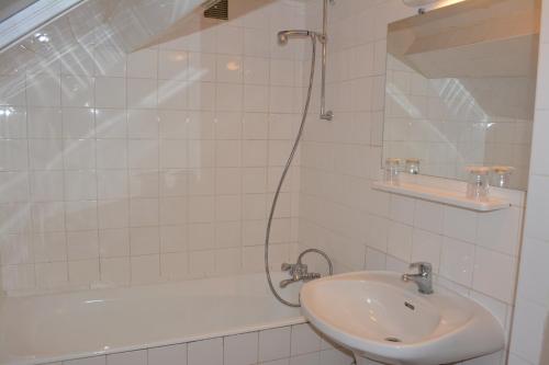 La salle de bains est pourvue d'un lavabo, d'une baignoire et d'une douche. dans l'établissement Hôtel Stanislas sans ascenseur, à Paris