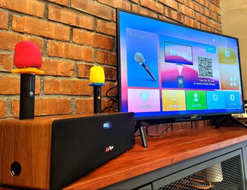 a flat screen tv sitting on top of a table with two microphones at [New!] Jonker Street Loft 3BR Melaka 10PAX in Melaka