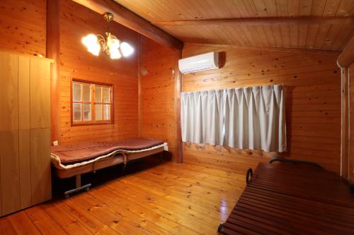 ein Zimmer mit einer Bank in einem Blockhaus in der Unterkunft ウィークリー宿家里 in Akaren