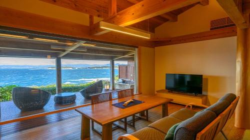a living room with a television and a table and chairs at Hamachidorinoyu Kaisyu in Shirahama