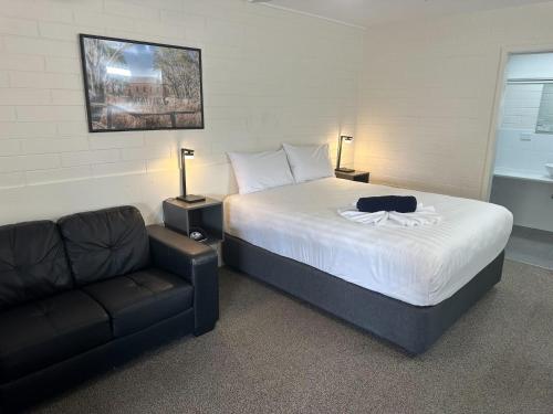 Un dormitorio con una cama, un sofá y una silla. en Vineland Motel Mildura, en Mildura