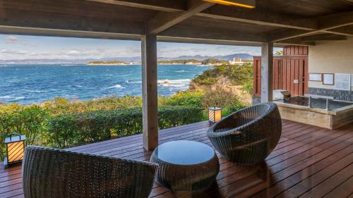 a deck with chairs and a table and the ocean at Hamachidorinoyu Kaisyu in Shirahama