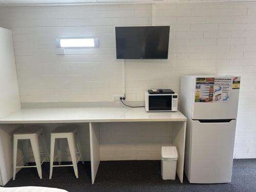 a kitchen with a table with a microwave and a refrigerator at Vineland Motel Mildura in Mildura