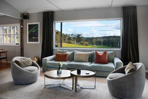 a living room with a couch and chairs and a large window at The Welcome Paddock in Hepburn