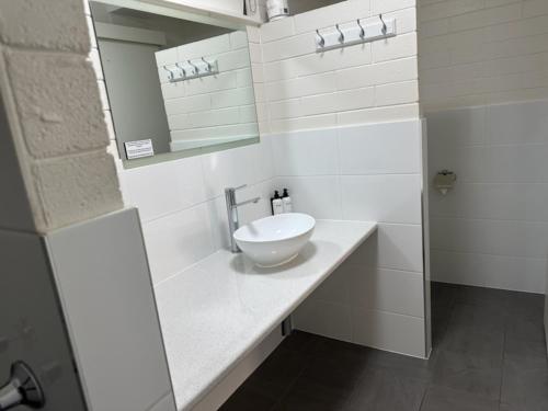 Un baño blanco con lavabo y espejo. en Vineland Motel Mildura, en Mildura