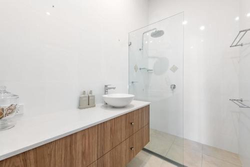Un baño blanco con lavabo y ducha. en Keesing Villa 7, en Byron Bay