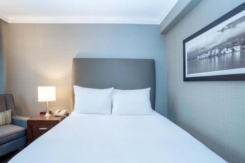 a bedroom with a bed and a couch and a tv at Sandman Hotel Vancouver Airport in Richmond