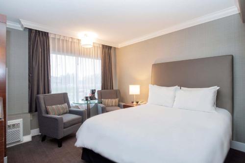 a hotel room with a large bed and a chair at Sandman Hotel Vancouver Airport in Richmond