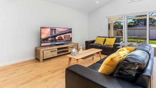 ein Wohnzimmer mit Sofa und Fernseher in der Unterkunft Luxe Hideaway - South Umina in Umina