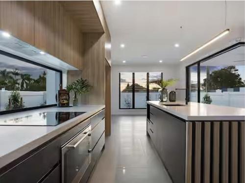 Una cocina grande con encimeras blancas y grandes ventanales. en Luxe Capri Villa Heated Pool,10-min Walk to Beach, en Gold Coast