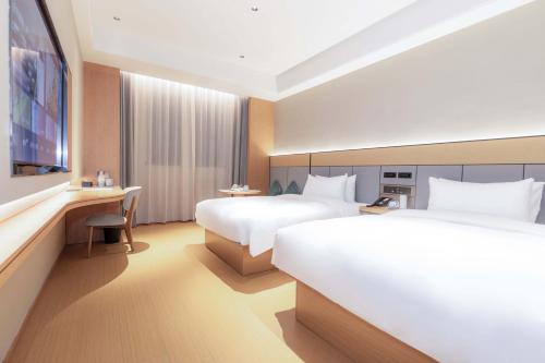 ein Hotelzimmer mit zwei Betten und einem Schreibtisch in der Unterkunft JI Hotel Shenzhen Bantian Huawei Base in Shenzhen