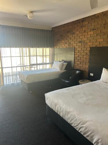 ein Hotelzimmer mit zwei Betten und einem Stuhl in der Unterkunft Travellers Rest Motor Inn Swan Hill in Swan Hill