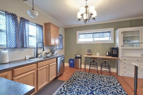 a kitchen with wooden cabinets and a blue and white rug at 5th St Bungalow - Historic Charm Near 3rd St in McMinnville