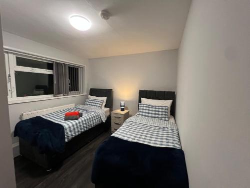 ein Schlafzimmer mit zwei Betten und einem Fenster in der Unterkunft Rare 4 en-suite Bedroom Flat with Free Parking and workspace in Warwick