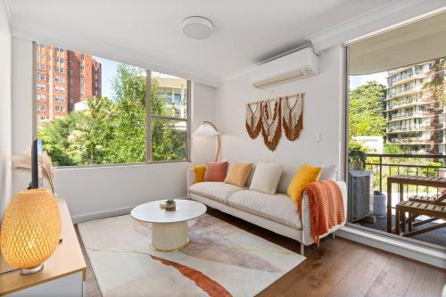 a living room with a couch and a large window at Stylish City Stay, Elizabeth Bay 2BR, Pool, balcony in Sydney