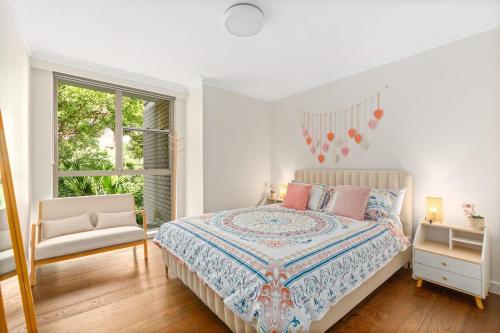 a white bedroom with a bed and a window at Stylish City Stay, Elizabeth Bay 2BR, Pool, balcony in Sydney