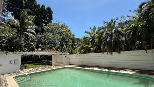 a swimming pool in front of a fence with palm trees at Stylish City Stay, Elizabeth Bay 2BR, Pool, balcony in Sydney