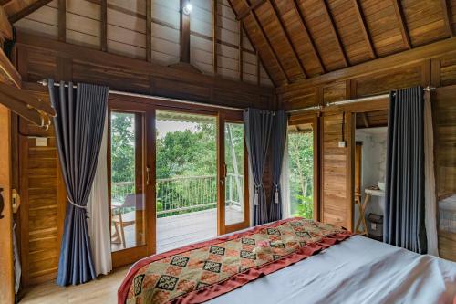 una camera da letto con un letto e una grande finestra di Jatiluwih Guava Eco Living managed by Manara a Jatiluwih