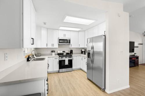 a kitchen with white cabinets and a stainless steel refrigerator at Mountain Cabin with Hot Tub in Flagstaff