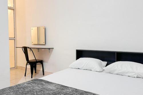 Un dormitorio con una cama blanca y una silla. en RedDoorz near Bandara Depati Amir, 