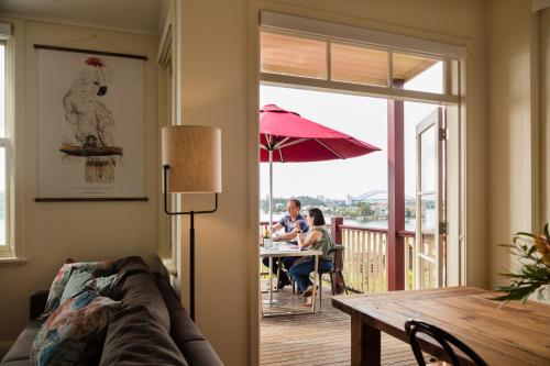 a living room with people sitting at a table on a deck at Cockatoo Island Accommodation in Sydney