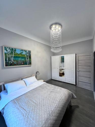 a bedroom with a white bed and a chandelier at Saulgrieži 7 in Ventspils