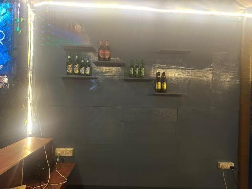 een bar met flessen alcohol aan de muur bij Laxmi house in Arambol
