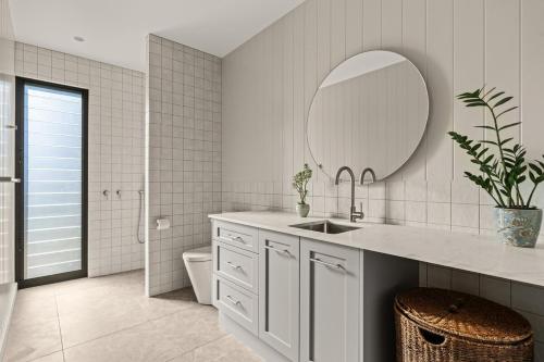 Un baño blanco con lavabo y espejo. en Chris' II, Designer Masterpiece in Kangaroo Valley, en Valle Kangaroo