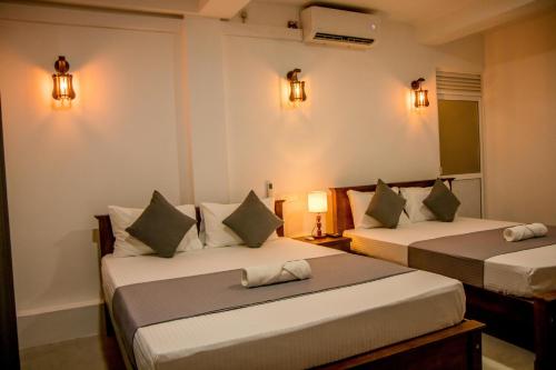 two beds in a room with lights on the wall at Shan Resort in Gintota