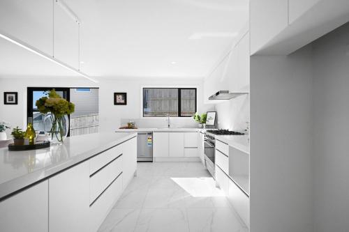 a white kitchen with white counters and white appliances at Dove's Rest-Brand New 4 Bedrooms Getaway to Eden in Hamilton