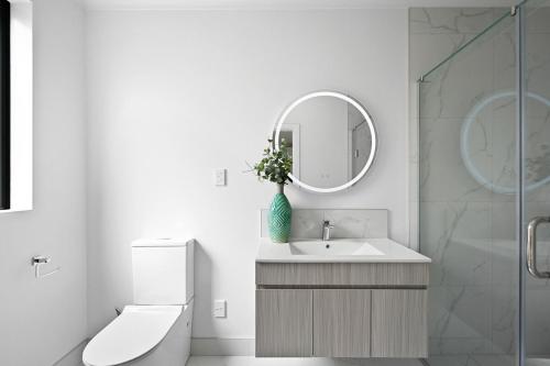 a white bathroom with a sink and a mirror at Dove's Rest-Brand New 4 Bedrooms Getaway to Eden in Hamilton