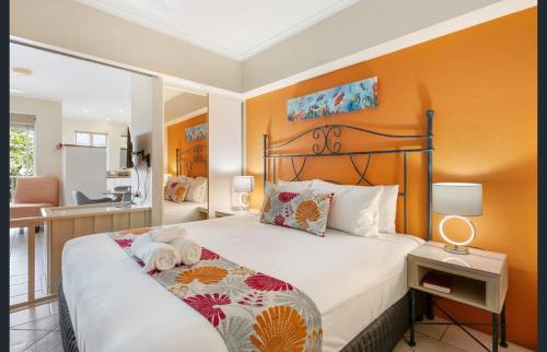 Coconut Palms - In the Heart of Port Douglas & Near the Beach في ميناء دوغلاس: غرفة نوم بسرير كبير بجدار برتقالي