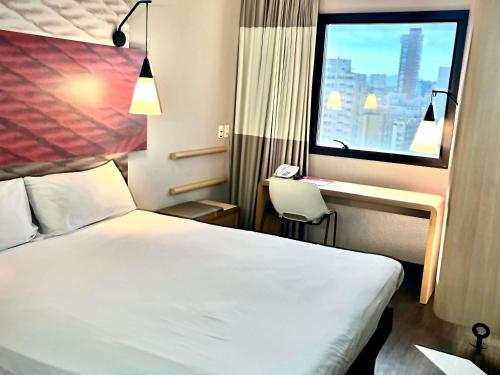 ein Hotelzimmer mit einem Bett, einem Schreibtisch und einem Fenster in der Unterkunft ibis Santos Gonzaga Praia in Santos