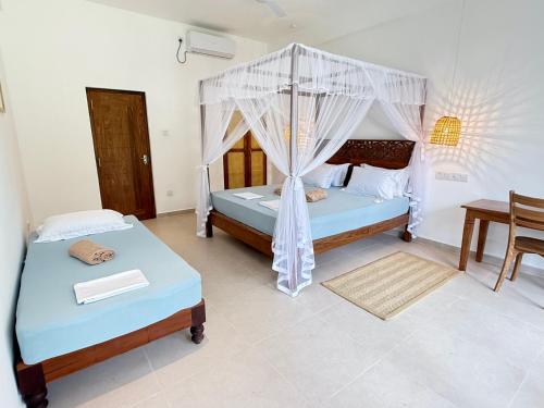 a bedroom with two beds and a table in it at Lily Mirissa in Mirissa