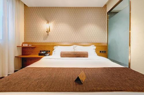 una camera da letto con un grande letto bianco e uno specchio di James Joyce Coffetel Qufu Tourist Center Gulou Street Sankong Scenic Spot a Qufu