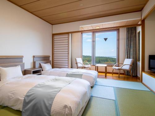 a hotel room with two beds and a television at KAMENOI HOTEL Aomori Makado in Noheji