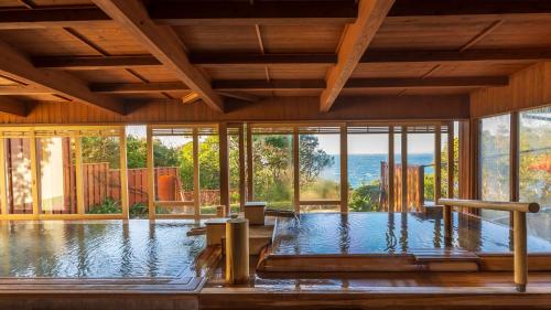 a swimming pool in a house with glass windows at Hamachidorinoyu Kaisyu in Shirahama