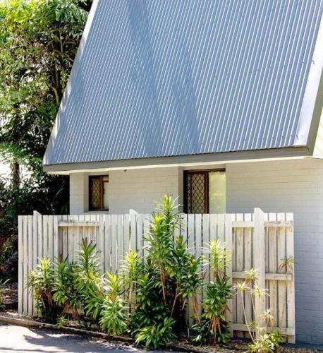 a white house with a fence and a blue roof at Bayshore Bungalow 9 - Oceanstays in Byron Bay