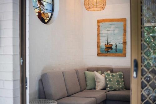 Bayshore Bungalow 5 - Oceanstays في خليج بايرون: غرفة معيشة مع أريكة ولوحة على الحائط