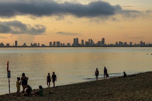 a group of people on a beach with a city in the background at Nhà Khách 258 - Sea Front - Near Mikazuki - 500m in Da Nang